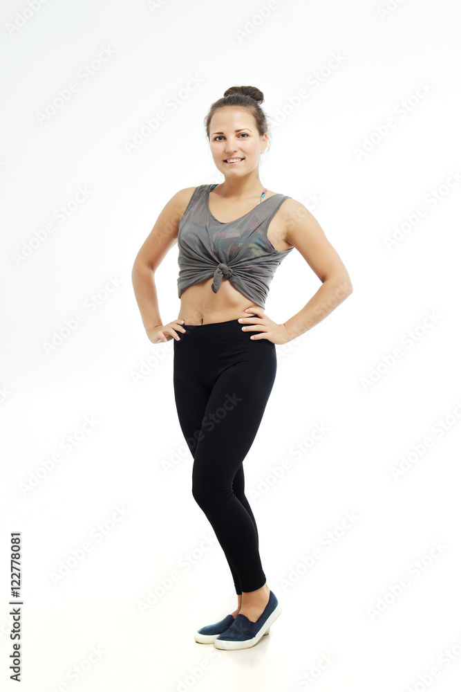 Fitness woman in sport style standing isolated on white background. Brunette girl standing in leggings.
