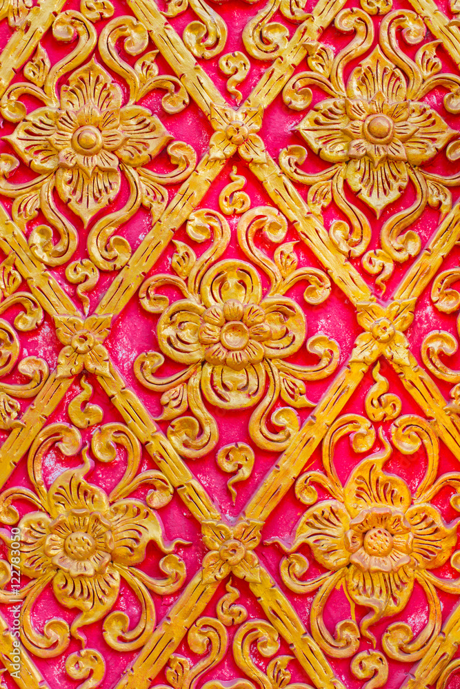 Thai flower pattern Embossed cement paint with gold and red color background in temple.