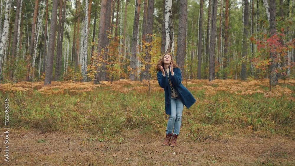 Happy girl dancing and having fun in autumn forest. mid shoot, slowmotion