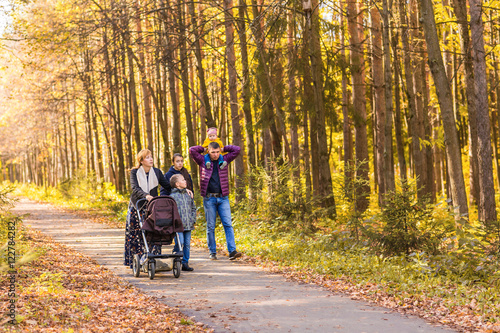 Happy young family walking down the road outside in autumn nature.