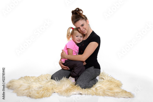 Matka z córką siedzą na dywanie.