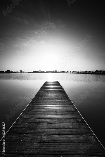 Black and white photography, pier at sunrise in a park of Manresa,Catalonia, Spain. Nice walking area with trees and water pond