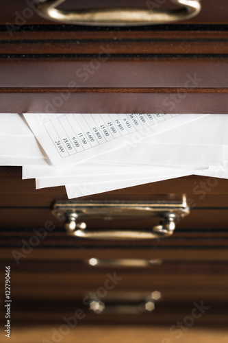 A drawer of wooden commode  full of paper documents. Selective focus photo