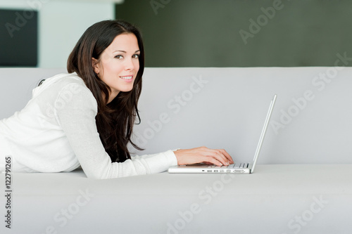 Young Woman Lounging in Living Room on Couch with Laptop