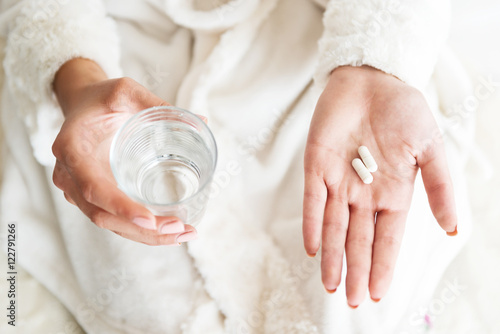 Woman holding a glass of water and pills, detail  