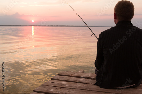 fisherman with rod over the lake at sunset