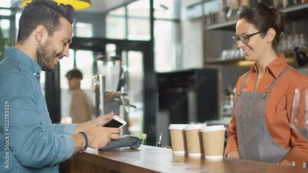 Handsome Young Man Paying for Takeaway Coffee with Mobile Phone at Coffee Shop. Shot on RED Cinema Camera in 4K (UHD). Handsome Young Man Paying for Takeaway Coffee with Mobile Phone at Coffee Shop. Shot on RED Cinema Camera in 4K (UHD).