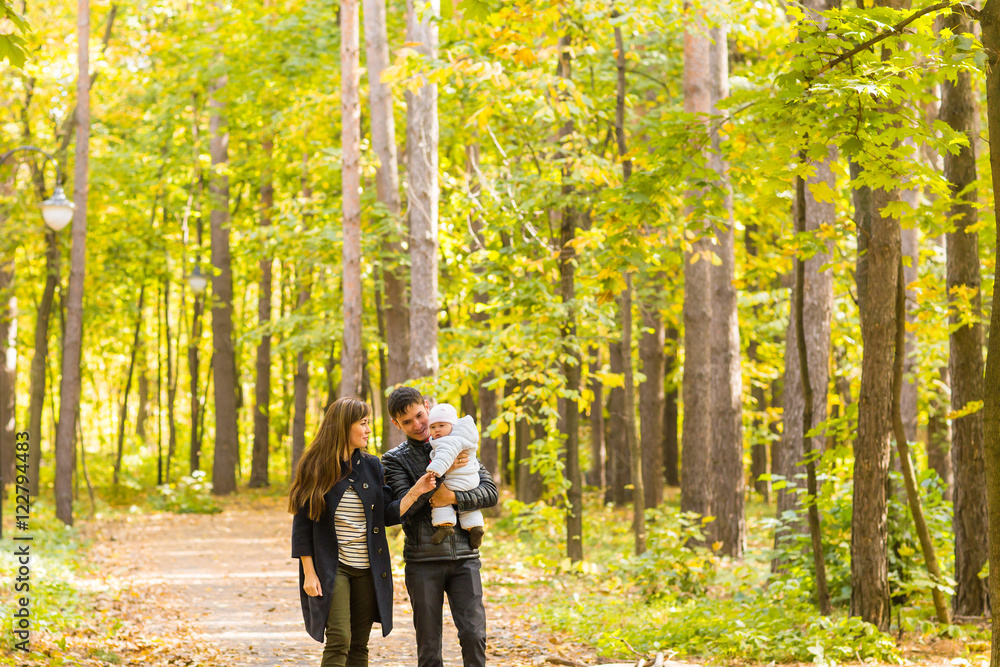 Fototapeta premium Happy young family walking down the road outside in autumn nature.