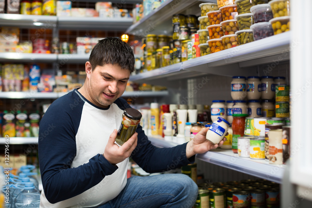 Young man buying tinned food .