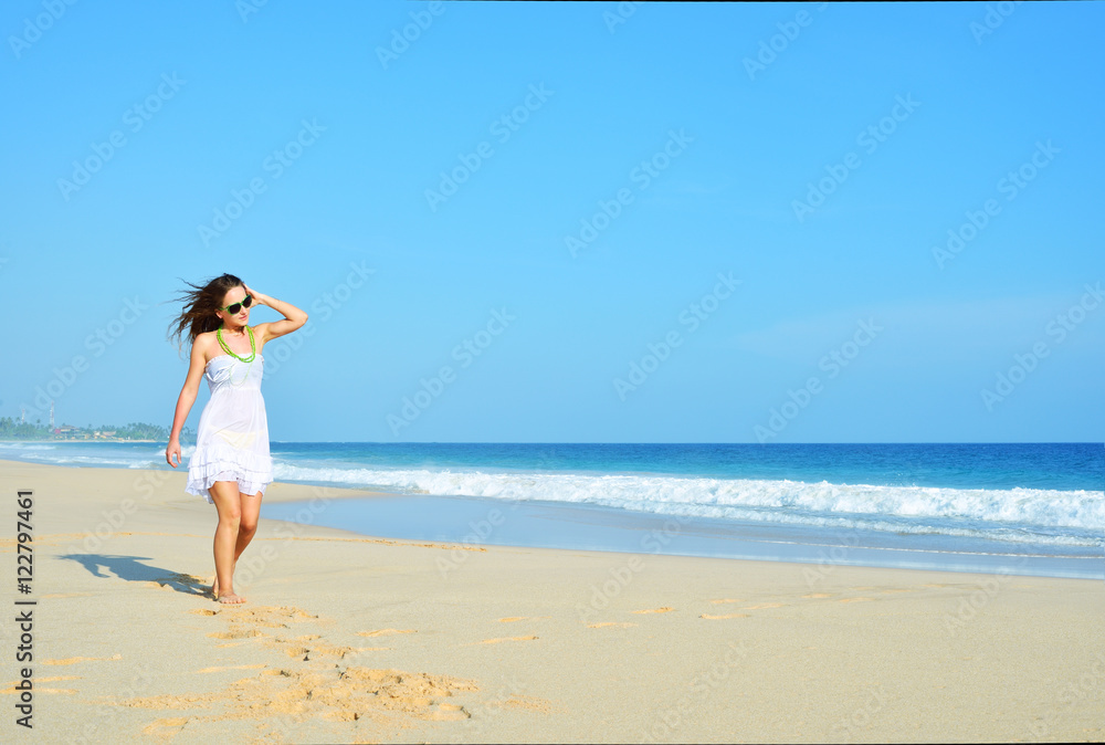 Happy carefree woman walking on beach celebrating her freedom. Summer woman background of the ocean and sand. Young girl looking at the sky.