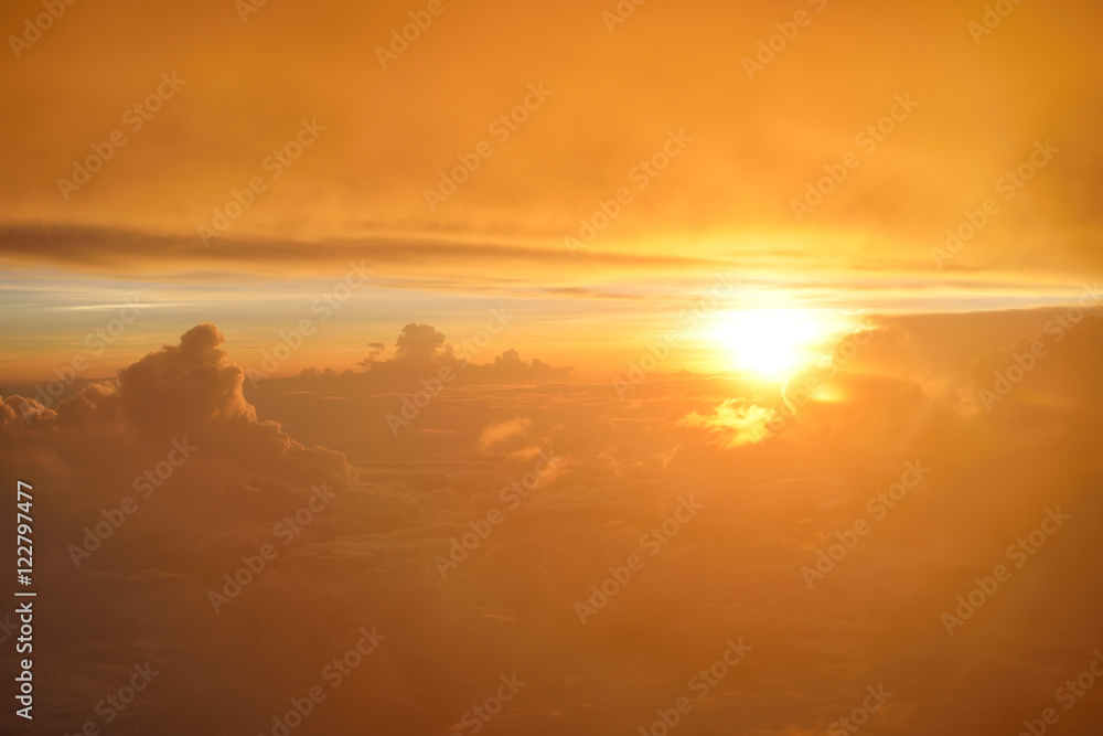 Spectacular view of sunset or sunrise above clouds from airplane window. Top view.