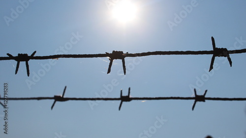 Barbed wire on background solar sky