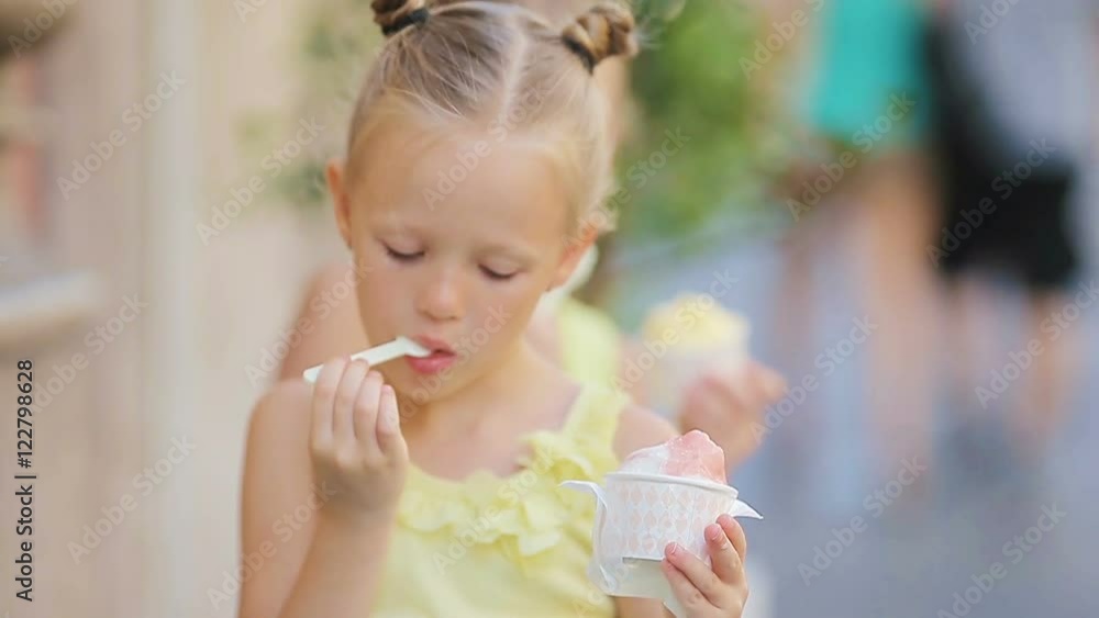 Adorable little girls eating ice-cream outdoors at summer. Cute kids enjoying real italian gelato near Gelateria in Rome Adorable little girls eating ice-cream outdoors at summer. Cute kids enjoying real italian gelato near Gelateria in Rome