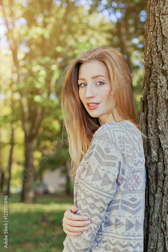 Beautiful woman with blue eyes standing in a park in autumn