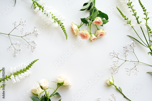 Assorted roses heads on white background. Flowers and leaves scattered on a table, overhead view wallpaper. Flat lay, top view.