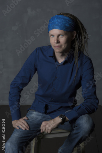 Man's portrait with colorful dreadlocks, hippie style. Modern young boy wears a bandana on the head.