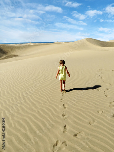 little girl walk and leaves footprints on desert sand dune