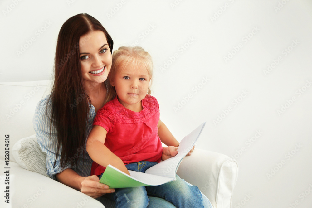 Mother with daughter reading book on chair Mother with daughter reading book on chair