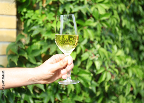 Male hand holding glass of white wine, outdoor
