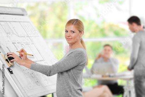 Foto Young female engineer working with architectural project and other engineers on