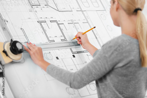 Young female engineer working with new project on drawing board