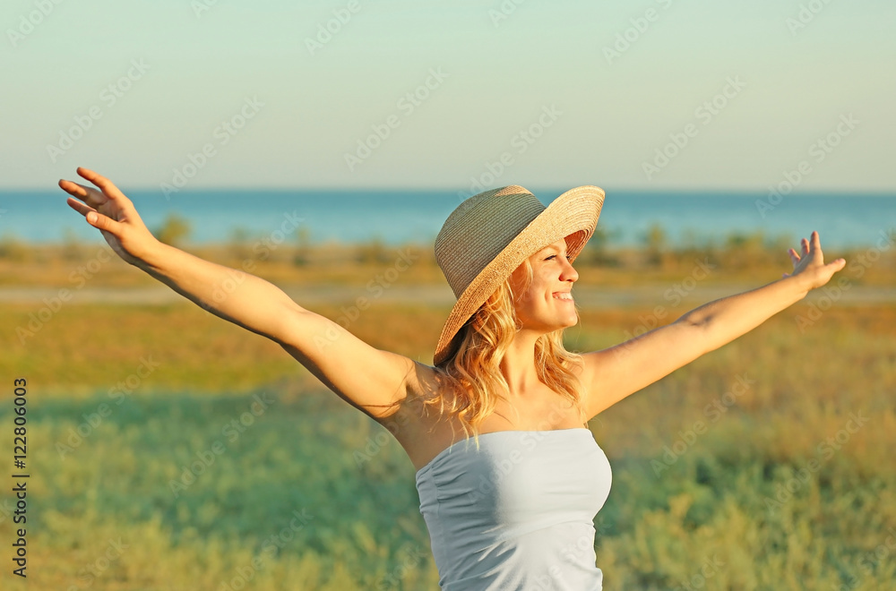 Fototapeta premium Young woman with hat in field on blue sky background