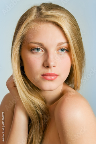Young woman pretty studio portrait. Girl touching her healthy long blonde hair.