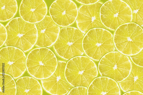 Abstract yellow background with citrus-fruit of lime slices. Close-up pattern.