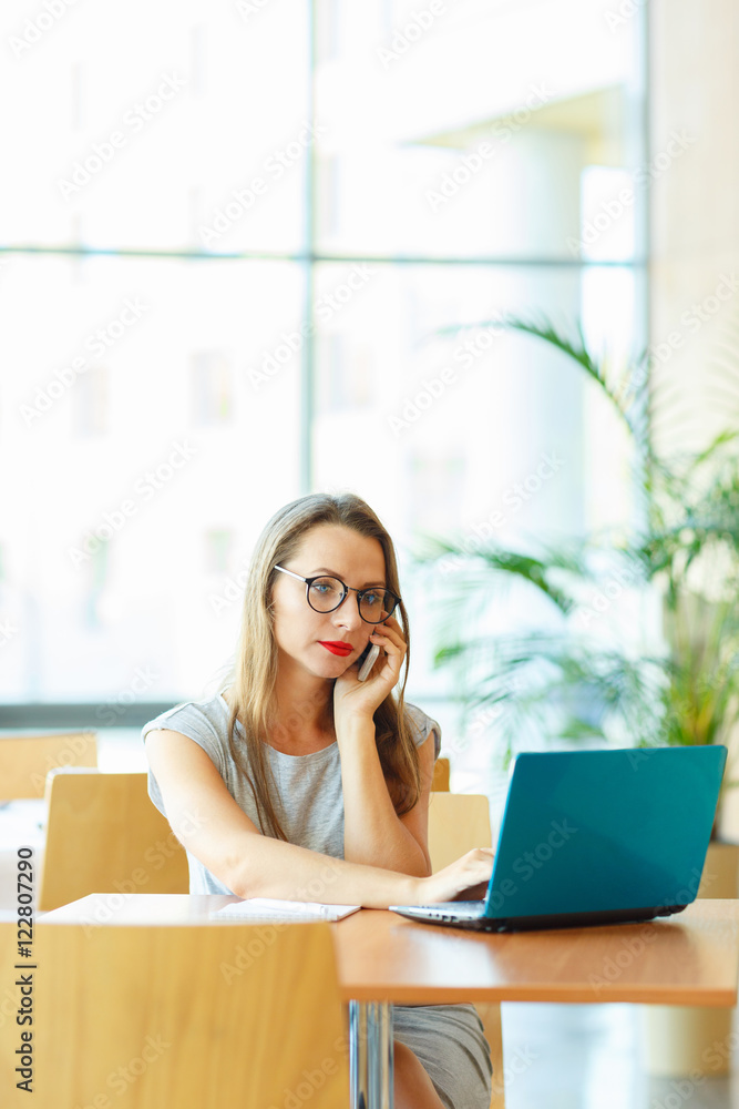 Woman working with a laptop and talking on the cell phone Woman working with a laptop and talking on the cell phone