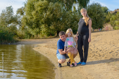 Pretty little girl with her parents at a lake