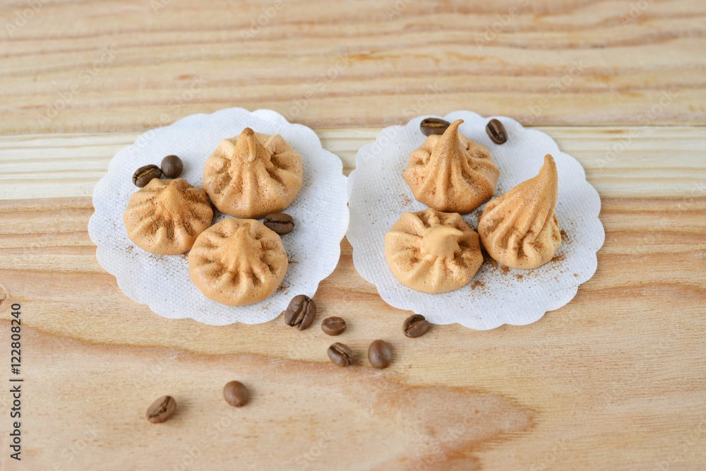 Vanilla meringue cookies on wooden background with copy space. Cakes with white ribbon and coffee. Vanilla meringue cookies on wooden background with copy space. Cakes with white ribbon and coffee.