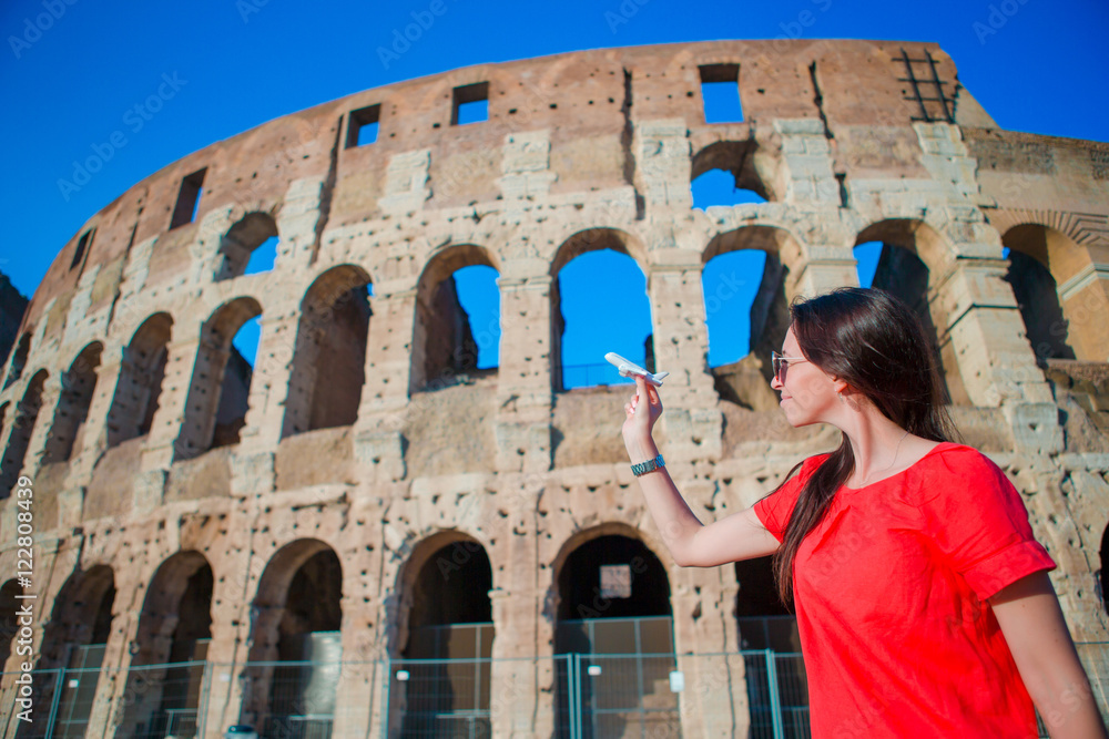 Young beautiful woman with small toy model airplane background Colosseum in Rome, Italy