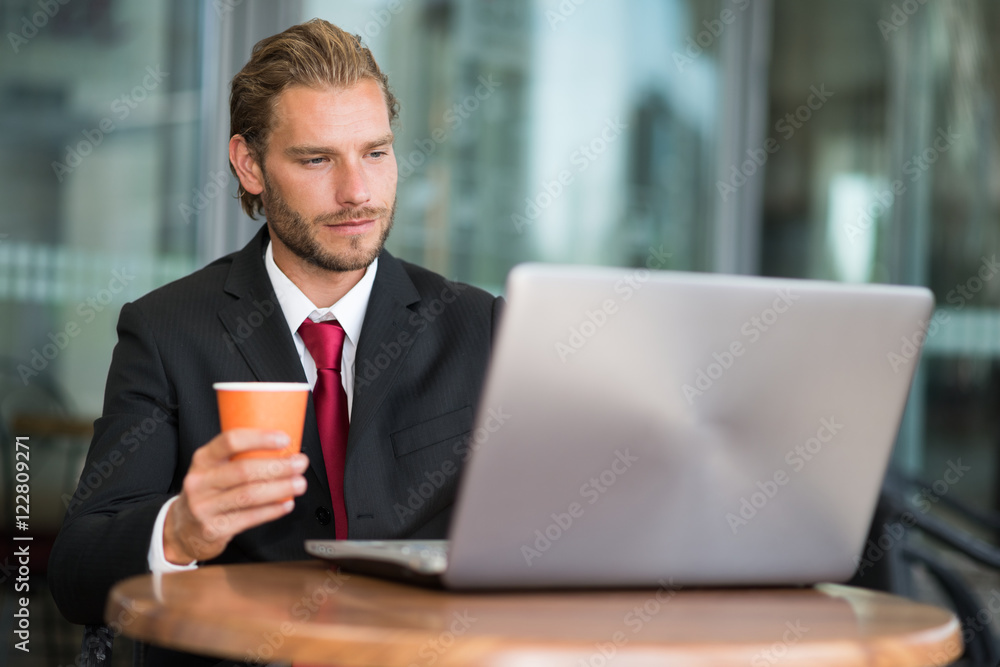Businessman using his laptop while drinking coffee Businessman using his laptop while drinking coffee