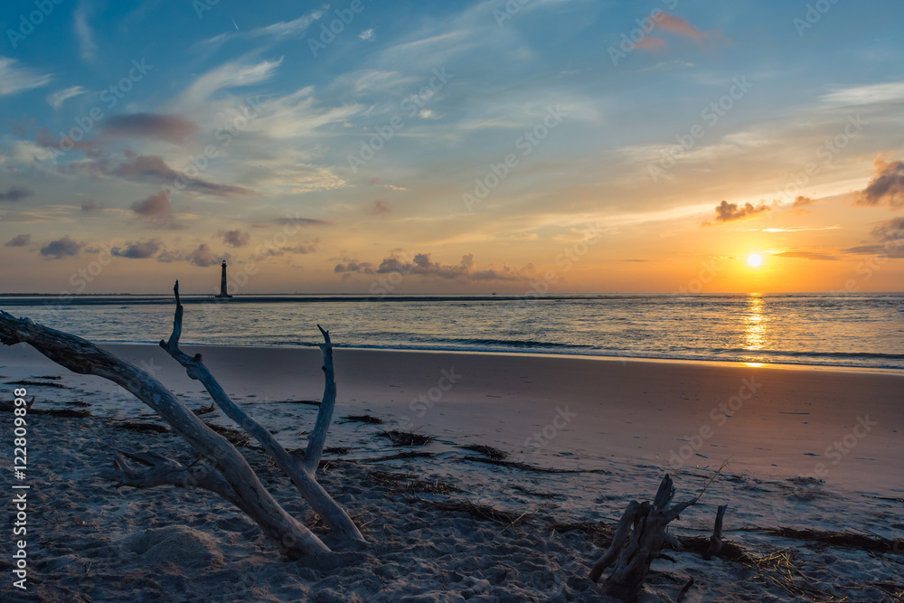 Beautiful beach sunrise with a lighthouse. Morris Island lighthouse viewed from Folly Beach, South Carolina.