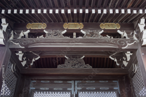 Kyoto, Japan - September 14, 2016: Ceiling detail of the Kenrei-mon gate at the Imperial Palace grounds. Wood carving in dark brown wood and golden plate decorations.
