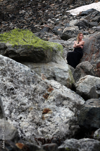 blond woman in black dress among the huge stones on the glacier. Mestia