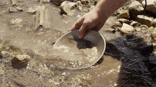 Closeup of a miner panning for gold in a stream.