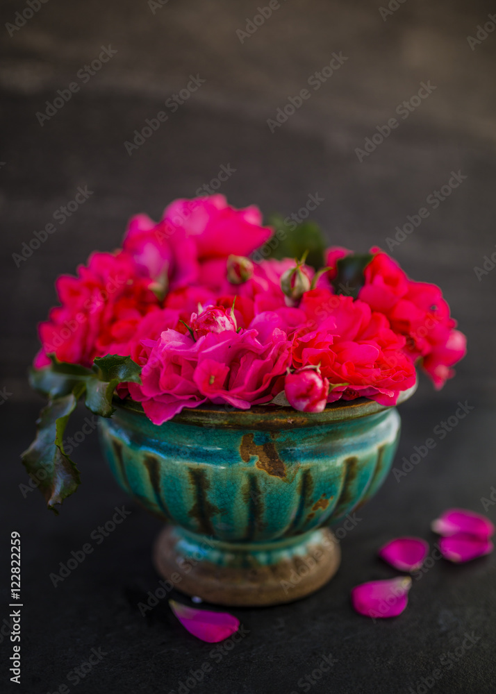 Beautiful pink roses in an old vase. Still life on dark background.