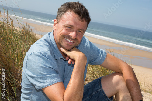 Lovely and attractive middle aged man sitting on beach