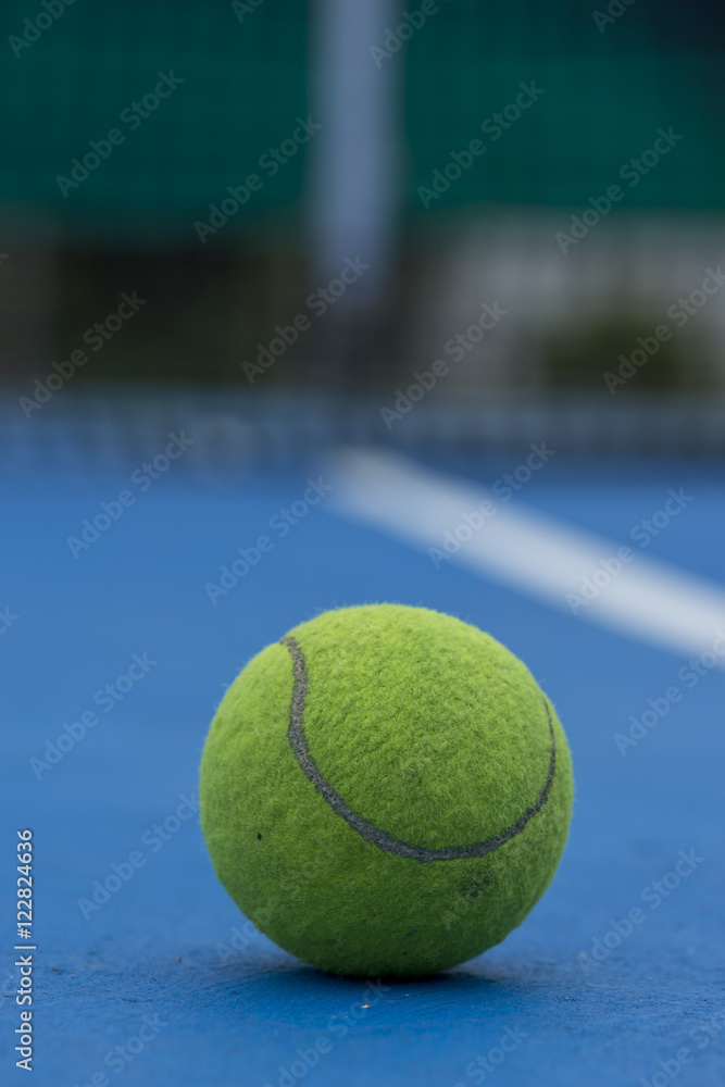A Tennis ball and a racket at blue tennis court.