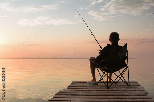 Murais de parede fisherman with rod over the lake at sunset