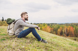 Young man traveler sitting on top of the hill. Travel and active lifestyle concept