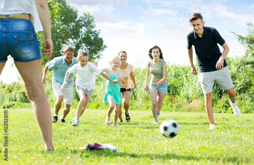 Parents with children playing football on outdoor