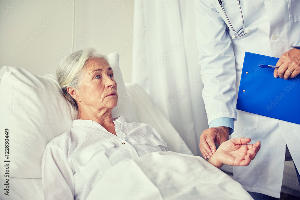 doctor checking senior woman pulse at hospital