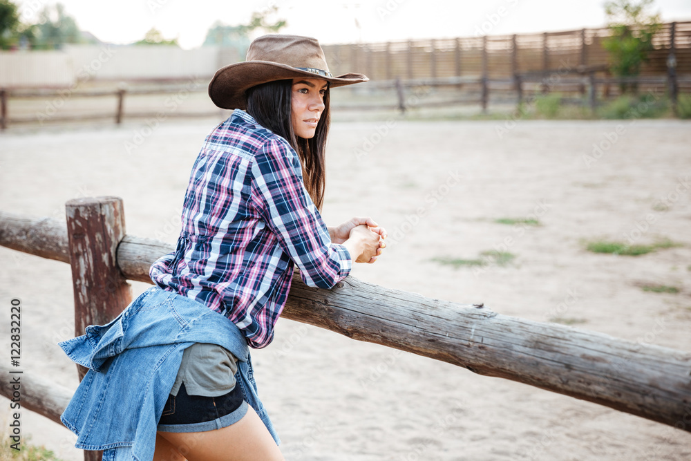 Beautiful young woman cowgirl in hat and plaid shirt
