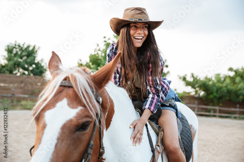 Smiling cute young womna cowgirl riding a horse outdoors © Drobot Dean