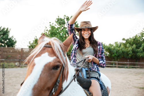 Smiling woman cowgirl riding a horse outdoors © Drobot Dean