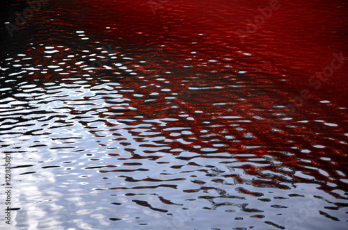 Blood red ripples and sky reflections on water