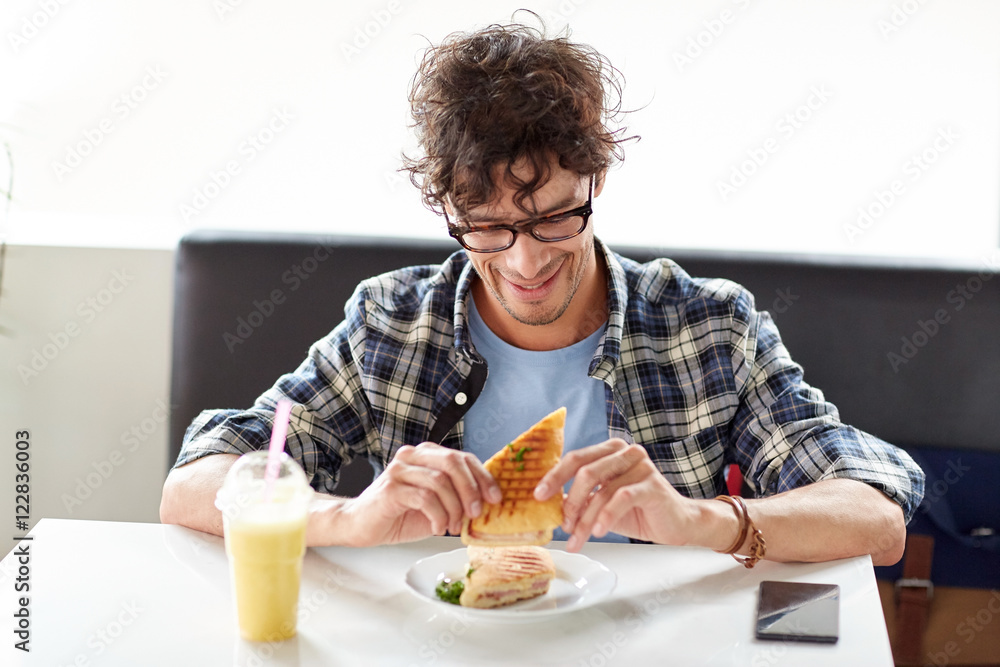 happy man eating sandwich at cafe for lunch happy man eating sandwich at cafe for lunch