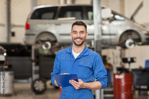 happy mechanic man with clipboard at car workshop photo